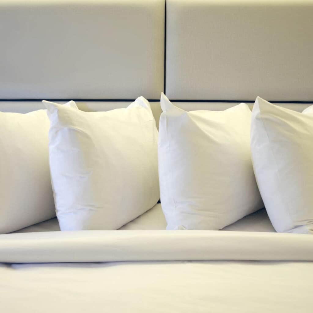 Verschillende hoofdkussens op een rij op bed