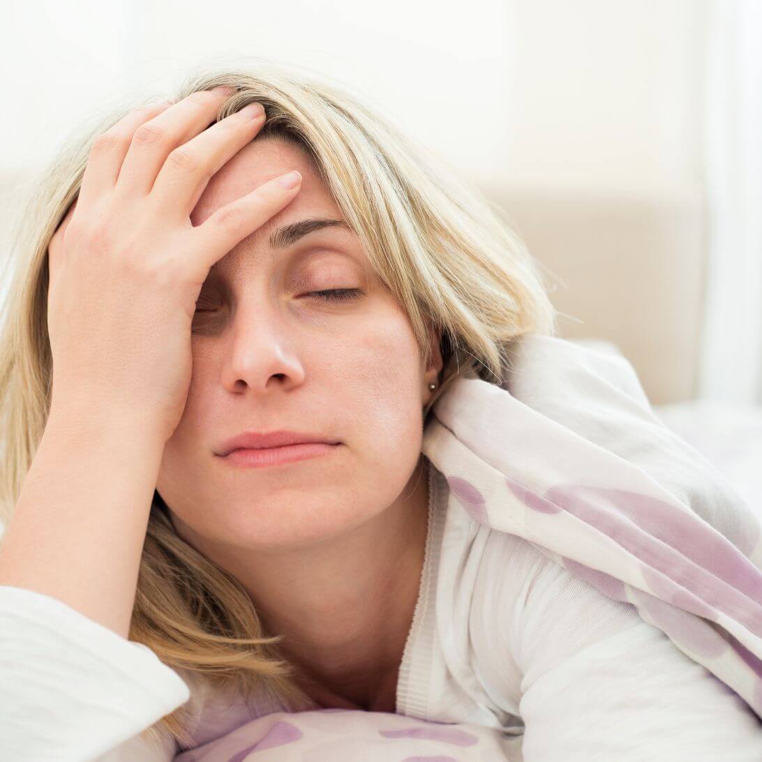 Vrouw met slaapproblemen ligt met hoofd in hand in bed