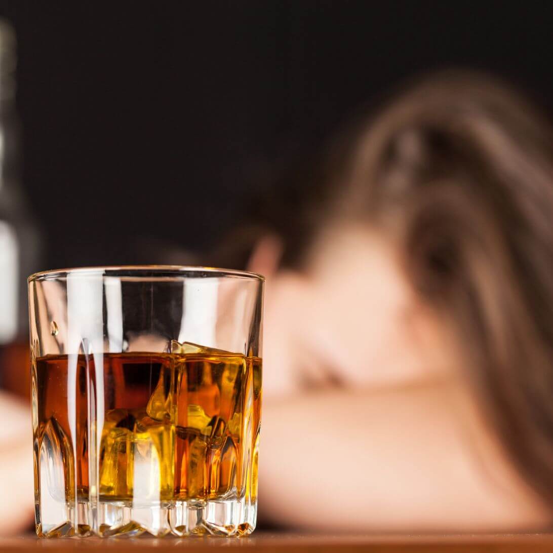 Vrouw slapend achter glas alcohol met ijs