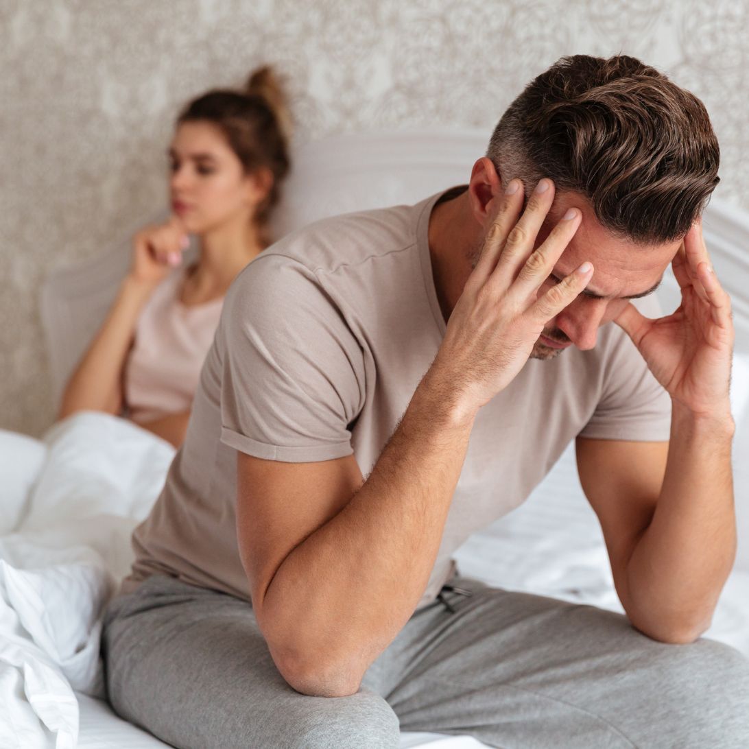 Vrouw en man in bed, man met hoofd in handen, impact van slaap op slecht seksleven