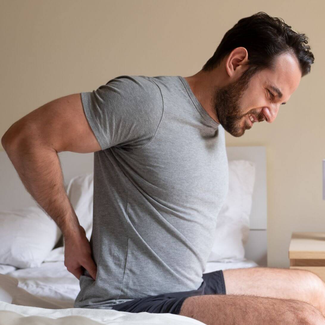 Man zit op matras en heeft last van pijnklachten