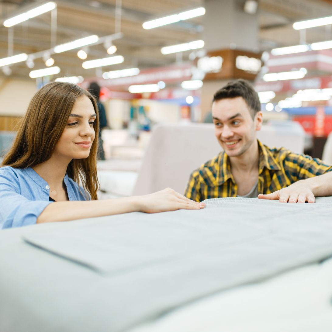 Vrouw en man testen nieuw bed en matras in winkel