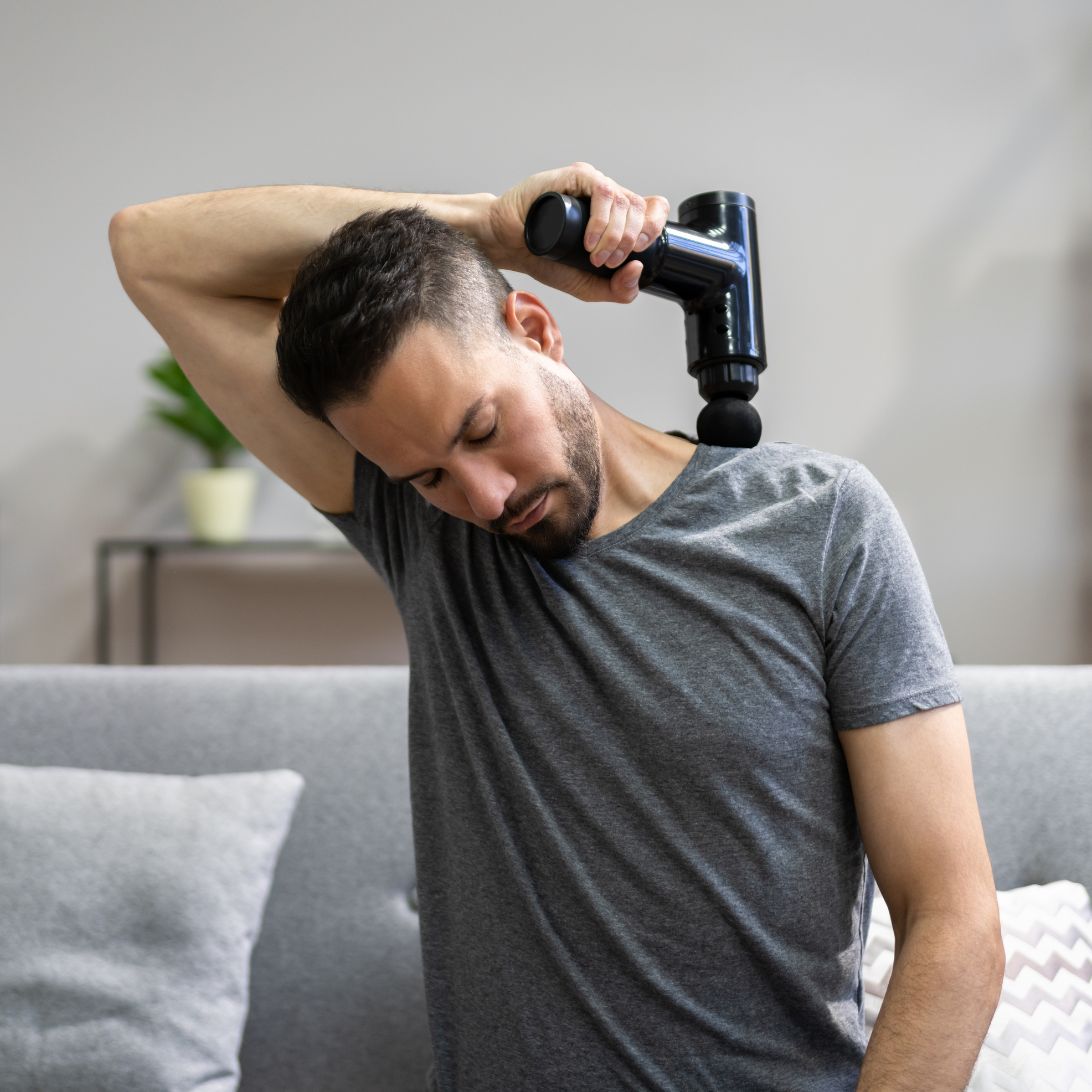 Man gebruikt massage gun op schouders