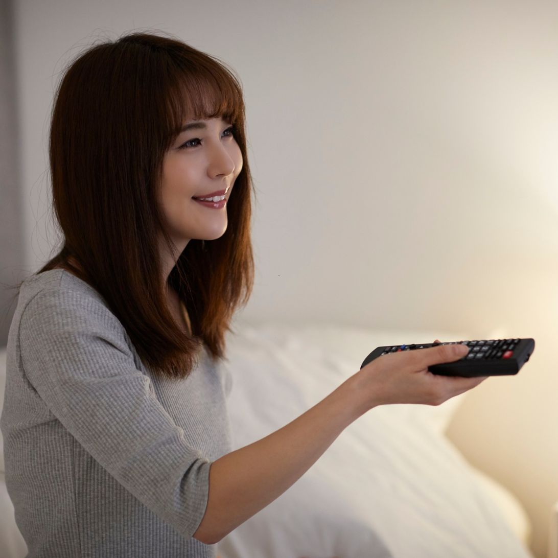 Boxspring tv-lift 1 Vrouw zit op boxspring en gebruikt afstandsbediening voor tv-lift