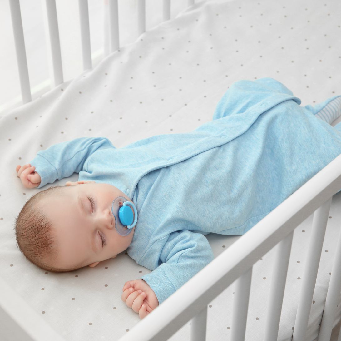 Baby ligt te slapen in babybed