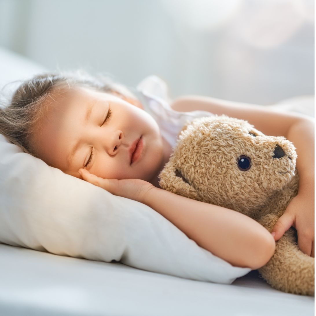 Kind ligt met teddybeer te slapen op kindermatras