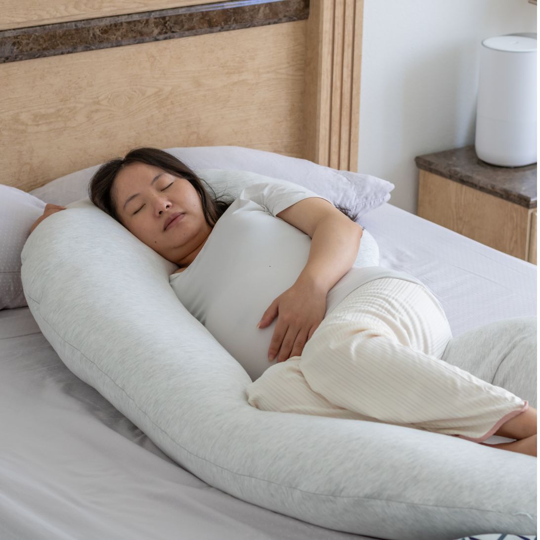 Vrouw ligt te slapen op zwangerschapskussen